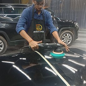 Trainer polishing a car hood in the studio